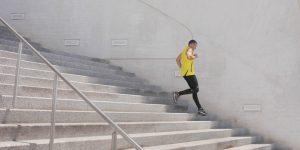 Man in yellow t-shirt running on concrete steps